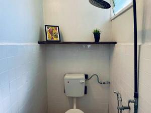 a bathroom with a toilet in a white tiled wall at Blissful Cottage in Pantai Cenang