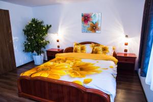 Un dormitorio con una cama con flores amarillas. en Pensiunea SilvAnka, en Vîlcele