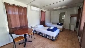 グンディウィンディにあるFreedom Lifestyle Parks Goondiwindiのベッド2台とテーブルが備わる小さな客室です。