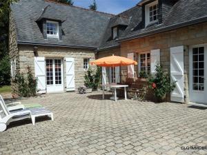 een patio met een tafel en een parasol voor een huis bij Maison Fouesnant, 5 pièces, 8 personnes - FR-1-481-47 in Fouesnant