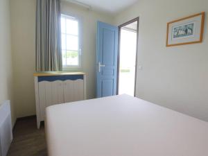 a bedroom with a white bed and a blue door at Fouesnant, Appartement avec piscine chauffée, plage à pied - FR-1-481-83 in Fouesnant