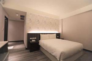 a bedroom with a white bed and a wall at Chair Man Hotel in Taipei