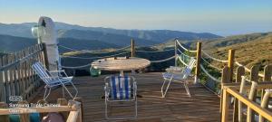 a table and chairs on a wooden deck with a view at Cortijo Saucillo in Albondón