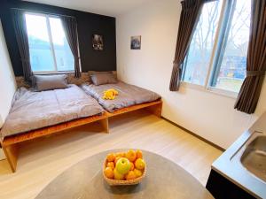 um quarto com duas camas e uma tigela de fruta numa mesa em Q FOX GMG HOTEL em Niseko