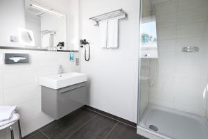 a white bathroom with a shower and a sink at Schloss Hotel Burgbrohl in Burgbrohl