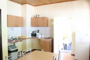 a kitchen with wooden cabinets and a table with chairs at Fortuna Hostel in Vilnius