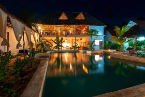 a swimming pool in front of a house at night at Heart of Zanzibar Bungalows in Paje