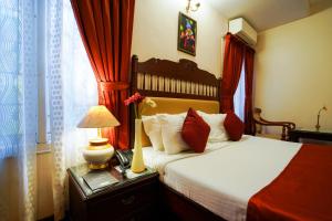 a bedroom with a large bed with red curtains at Hotel Arches in Cochin