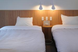 Habitación de hotel con 2 camas con sábanas blancas en Beach SPA TSUDA 0 Cero棟, en Sanuki