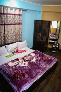 SHARTHI HOMESTAY AND LODGING في Namchi: غرفة نوم بسريرين مع بطانية ارجوانية