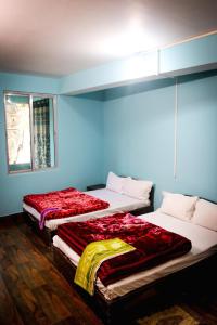 SHARTHI HOMESTAY AND LODGING في Namchi: سريرين في غرفة بجدران زرقاء