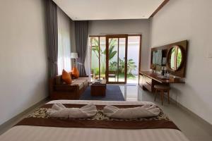 a bedroom with a bed and a living room with a television at Nau Nusa Villa in Nusa Penida