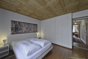 a bedroom with a white bed and a wooden ceiling at Allod Brattas - Sankt Moritz in St. Moritz