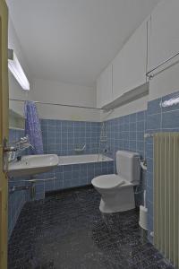 a blue tiled bathroom with a toilet and a sink at Allod Brattas - Sankt Moritz in St. Moritz