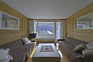 a living room with two couches and a large window at Allod Brattas - Sankt Moritz in St. Moritz