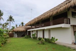 a building with a thatched roof and a yard at LaFinca Hostel Siargao in San Isidro