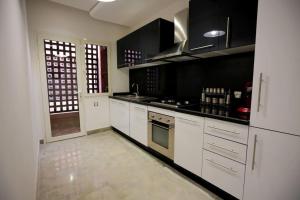 une cuisine avec des armoires blanches et des appareils noirs dans l'établissement APPARTEMENT RIAD WHITE GOLDEN, à Marrakech