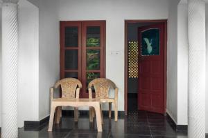 two chairs sitting in front of a red door at Secret Paradise in Varkala