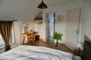 a bedroom with a bed and a table and a desk at Qui Dort d'Isnes in Isnes