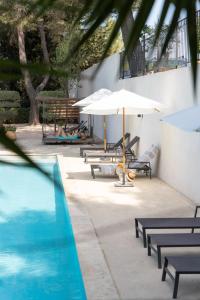 ein Pool mit Tischen, einem Sonnenschirm und Bänken in der Unterkunft Domaine Gaogaia in Aix-en-Provence