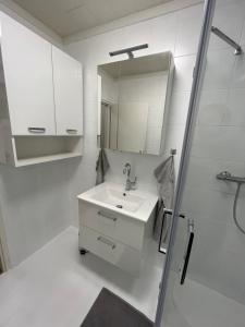 biała łazienka z umywalką i lustrem w obiekcie Modernes 4er Apartment in Skilift-Nähe w mieście Zell am See