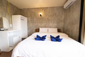 a bedroom with a white bed with blue bows on it at Mimo Guesthouse in Ko Chang