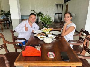 a man and a woman sitting at a table with food at Green Edge Villa in Hikkaduwa