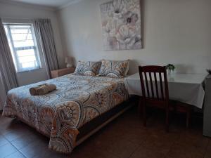 a bedroom with a bed and a table and a chair at White Rose Guest House in Vanderbijlpark