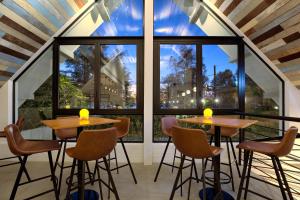 two tables and chairs in a room with large windows at Outrigger Surin Beach Resort - SHA Extra Plus in Surin Beach