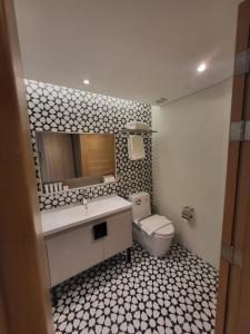 a bathroom with a sink and a toilet and a mirror at Infinity Tower Suites in Manila