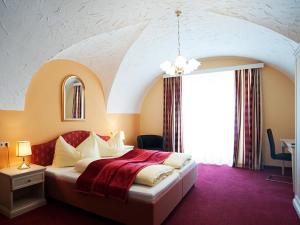 a bedroom with a large bed with a red carpet at Pension Frenzl - Kaiser von Österreich in Hermagor