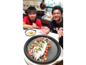 dois homens sentados numa mesa com um prato de peixe em Guesthouse Farmor - Vacation STAY 15083v em Imabari