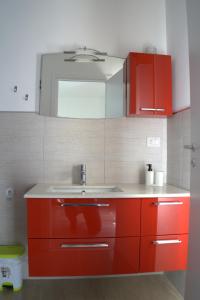 una cucina con armadi rossi e lavandino di A Due Passi a Grassano