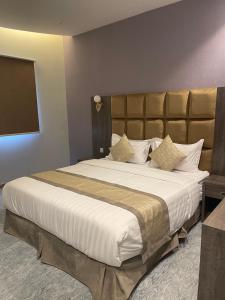 a bedroom with a large bed with a large white comforter at روش بلس للشقق المخدومة in Hafr Al Baten