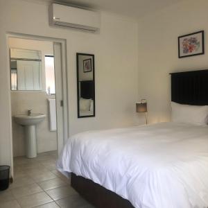 a bedroom with a white bed and a sink at Spring Acres Guesthouse in Nelspruit