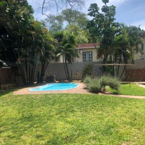 a yard with a swimming pool in front of a house at Spring Acres Guesthouse in Nelspruit