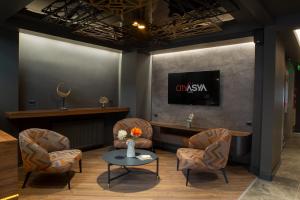 バンドゥルマにあるCITY ASYA HOTELの椅子、テーブル、テレビ付きの待合室