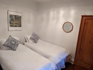 a bedroom with two beds and a mirror on the wall at Hamptons Historic Guest House in Littlehampton
