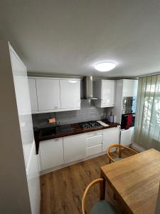 cocina con armarios blancos y mesa de madera en Whole house cottage with parking and huge garden, en Saint Mary Cray