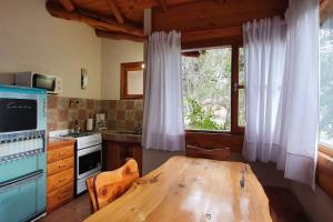 cocina con mesa de madera frente a una ventana en Cabaña Ciprés entre Bosques y Arroyo en El Bolsón