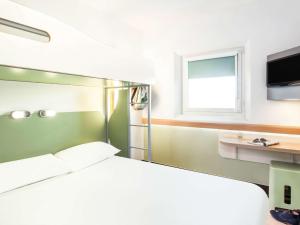 a bedroom with a bed and a desk and a window at ibis budget London Hounslow in Hounslow