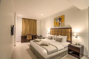 Corp Executive Hotel Doha Suites في الدوحة: غرفة الفندق بسرير كبير ومكتب