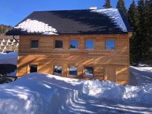 una casa de madera con un montón de nieve delante de ella en Lachtal-Zentral, en Lachtal