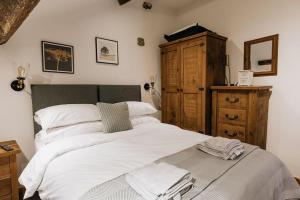 Schlafzimmer mit einem Bett mit weißer Bettwäsche und einer Kommode in der Unterkunft Fryers Cottage - Beautiful 2 bedroom Town & Country Cottage on edge of Peak District in Wirksworth