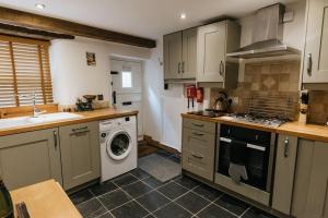 a kitchen with a washing machine and a washer at Fryers Cottage - Beautiful 2 bedroom Town & Country Cottage on edge of Peak District in Wirksworth