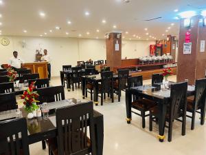 a restaurant with black tables and chairs and a counter at Bodhgaya Regency Hotel in Bodh Gaya