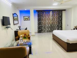 Schlafzimmer mit einem Bett, einem Schreibtisch und einem TV in der Unterkunft Bodhgaya Regency Hotel in Bodh Gaya