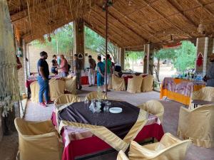 een groep mensen in een tent met tafels en stoelen bij Umaid Desert Camp, Raisar in Bikaner