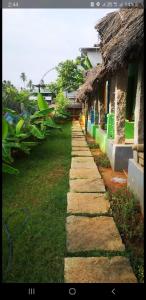 a stone walkway next to a building with grass at TANJORE HOME STAY in Thanjāvūr