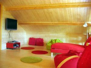 a living room with a red couch and a flat screen tv at Grand Valtin : chalet écolo 4 étoiles 14 personnes in Ban-sur-Meurthe-Clefcy